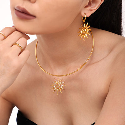 Model wearing gold spiral sun necklace and matching drop earring