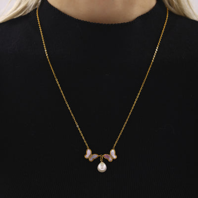 Gold double shell butterfly pearl necklace worn on black turtleneck