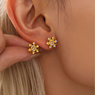 Clear zircon gold open-petal snowflake studs on ear and in fingers