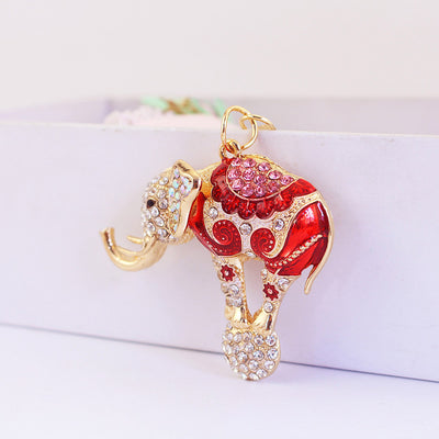 A red patterned elephant charm balances on a clear rhinestone ball.