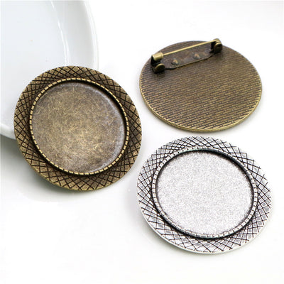 Round cabochon brooch tray with a crosshatched border and pin back in a group view on a white background