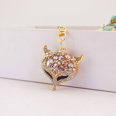 Front view of a gold-tone rhinestone fox head hanging against a pale box.