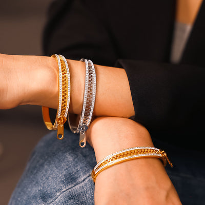 Gold and steel zipper rhinestone cuff bangles worn on crossed wrists