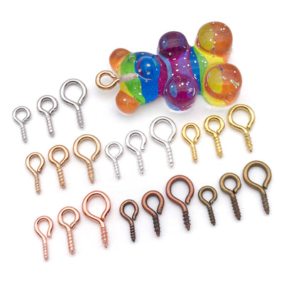 Metallic screw eye jewelry findings arranged on a light background