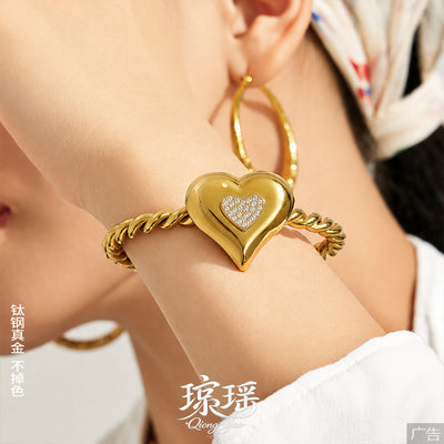 Gold puffy heart CZ twisted cuff bangle close-up on wrist