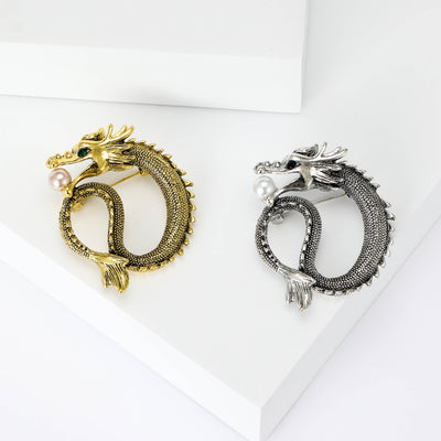 Gold and silver coiled dragon pearl brooches on white blocks
