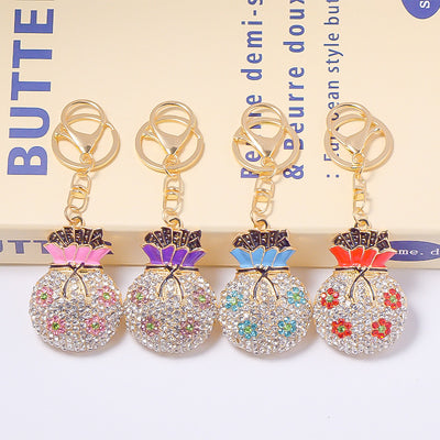 Four flower fortune bag keychains in pink, purple, blue, and red in a row