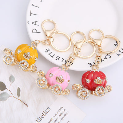Three pumpkin carriage keychains in yellow pink and red