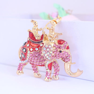 Close-up of a pink rhinestone elephant ornament with red saddle details and gold-tone trim.
