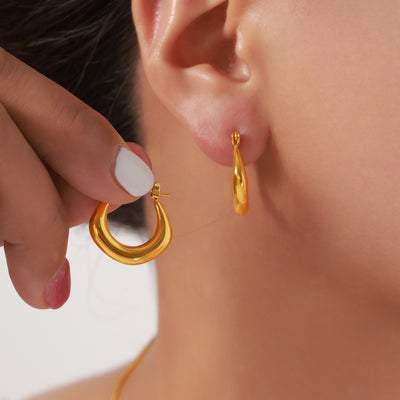 Model holding gold U crescent hoop earring beside matching worn stud-style view