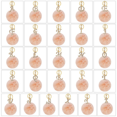 Grid of peach pom pom keychains with rhinestone letters A to Z