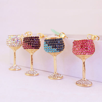 Four gold-tone wine glass charms decorated with white, purple, blue, and pink rhinestones.