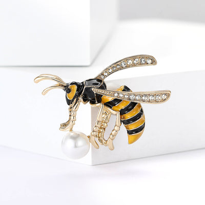 Front view of a striped bee with crystal wings and a dangling pearl