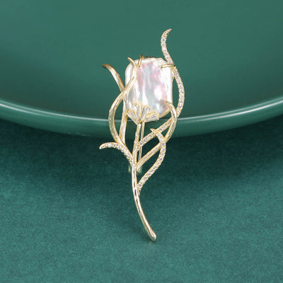 Gold pearl tulip bud brooch on green plate close-up