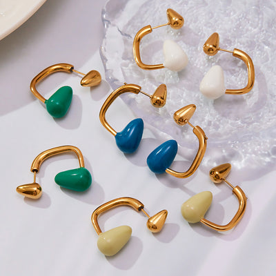 Assorted gold enamel teardrop C-frame earrings on glass