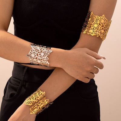 Model arms wearing gold and silver cutout flower leaf cuff bracelets