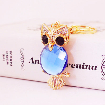 Front view of the blue faceted owl charm resting against a printed book.