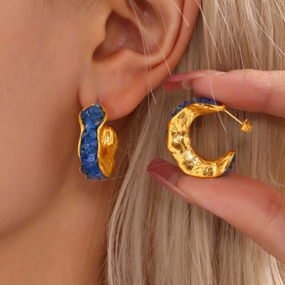 Blue crystal C hoop on ear and gold reverse side held in hand