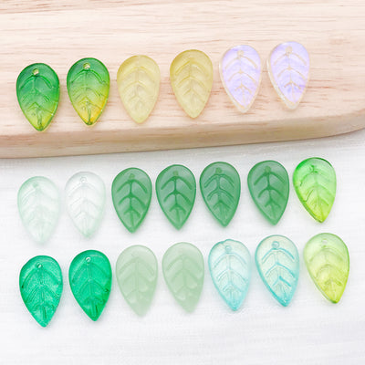 Green leaf and strawberry charms arranged on a light background