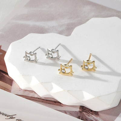 Silver and gold cat outline studs with clear stones on white hexagon tray