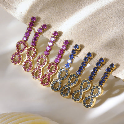 Gold figure-eight drop earrings in pink and blue zircon on fabric stand