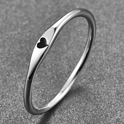 Silver thin band ring with small black heart enamel on gray surface