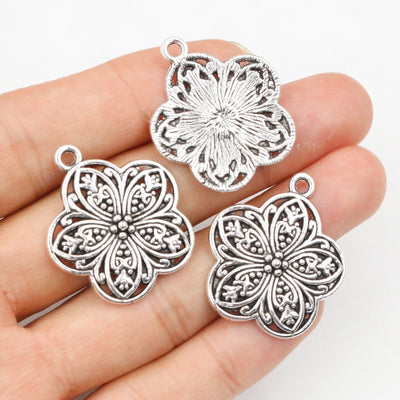 Grouped front view of openwork floral medallion metal charms with silver tone finish