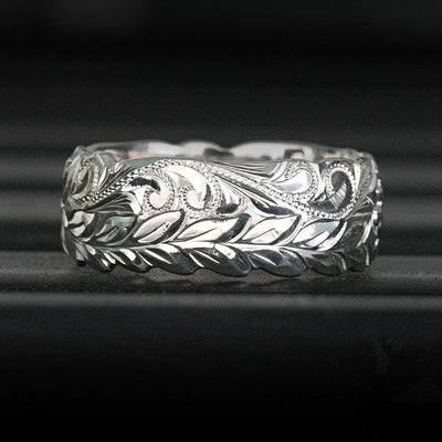Silver engraved leaf vine wide band ring front view on dark surface