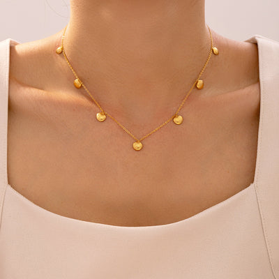 Model wearing gold multi shell charm necklace at collarbone