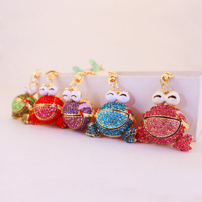 Five colorful stone-covered frog charms displayed in a row.