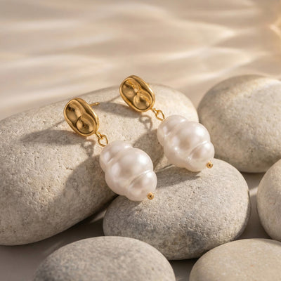 On-ear view of gold tone irregular disc and white drop earrings in main image 1.