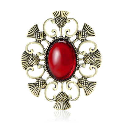 Antique bronze thistle brooch with red oval cabochon on white
