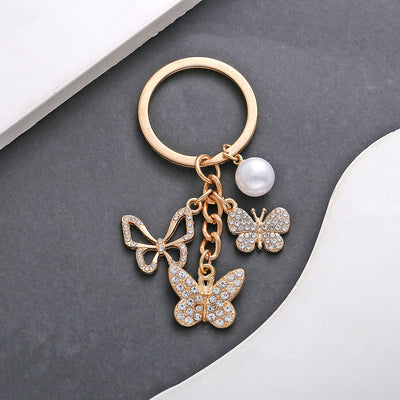 Front product photo of rhinestone openwork butterfly and faux pearl charm keychain showing the pictured design arrangeme