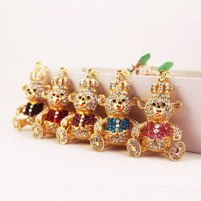 Five crowned bear charms with black, red, purple, blue, and pink stone vests are arranged in a row.