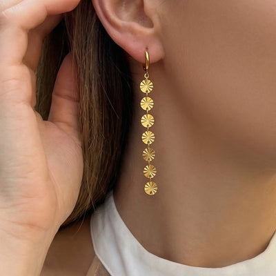 Gold seven-disc tassel hoop earring worn on ear side view