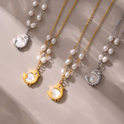 Gold and steel shell chick pearl necklaces flat lay on cream fabric