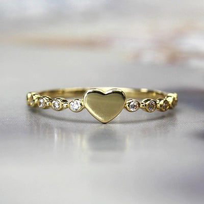 Gold heart center thin stacking ring front view on reflective surface