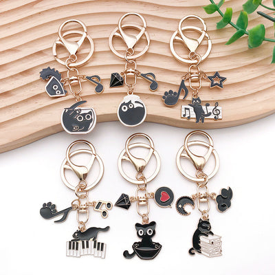 Main display of six black cat music keychains with instrument motifs