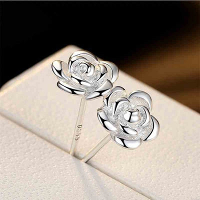 Silver rose flower stud earrings pair on white display close-up