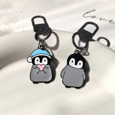 Two enamel penguin keychains with black clasps, plain and heart-hat styles