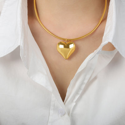 Model in white shirt wearing gold puffy heart snake chain necklace