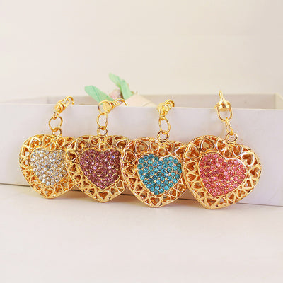 Four gold-tone openwork heart keychains with white, purple, blue, and pink rhinestone centers.