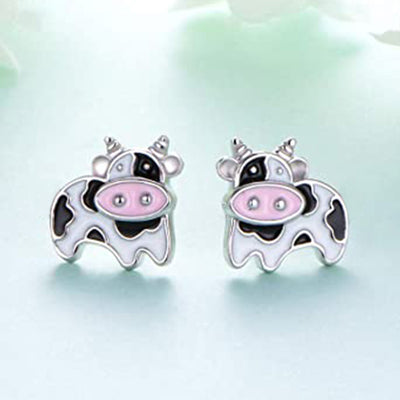 Pair of silver enamel spotted cow stud earrings on light blue surface