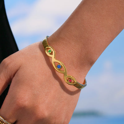 Gold evil eye enamel bangle worn on wrist outdoors