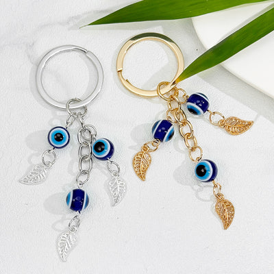 Gold-tone and silver-tone evil eye tassel keychains with three dangling glass eye beads each