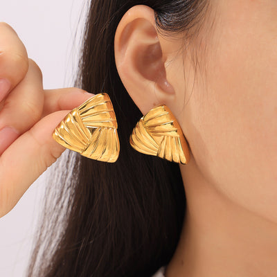 Model holding gold woven triangle earring next to worn stud