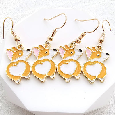 Four orange white enamel corgi heart-butt earrings lined up on white geometric stand
