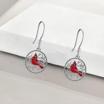 Product view showing round silver-tone filigree discs with a red bird perched on branches