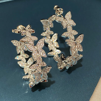 Close stacked view of silver pave butterfly open hoop pair