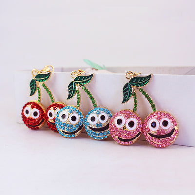 Three double-cherry charms display red, blue, and pink rhinestone faces with green leaves.